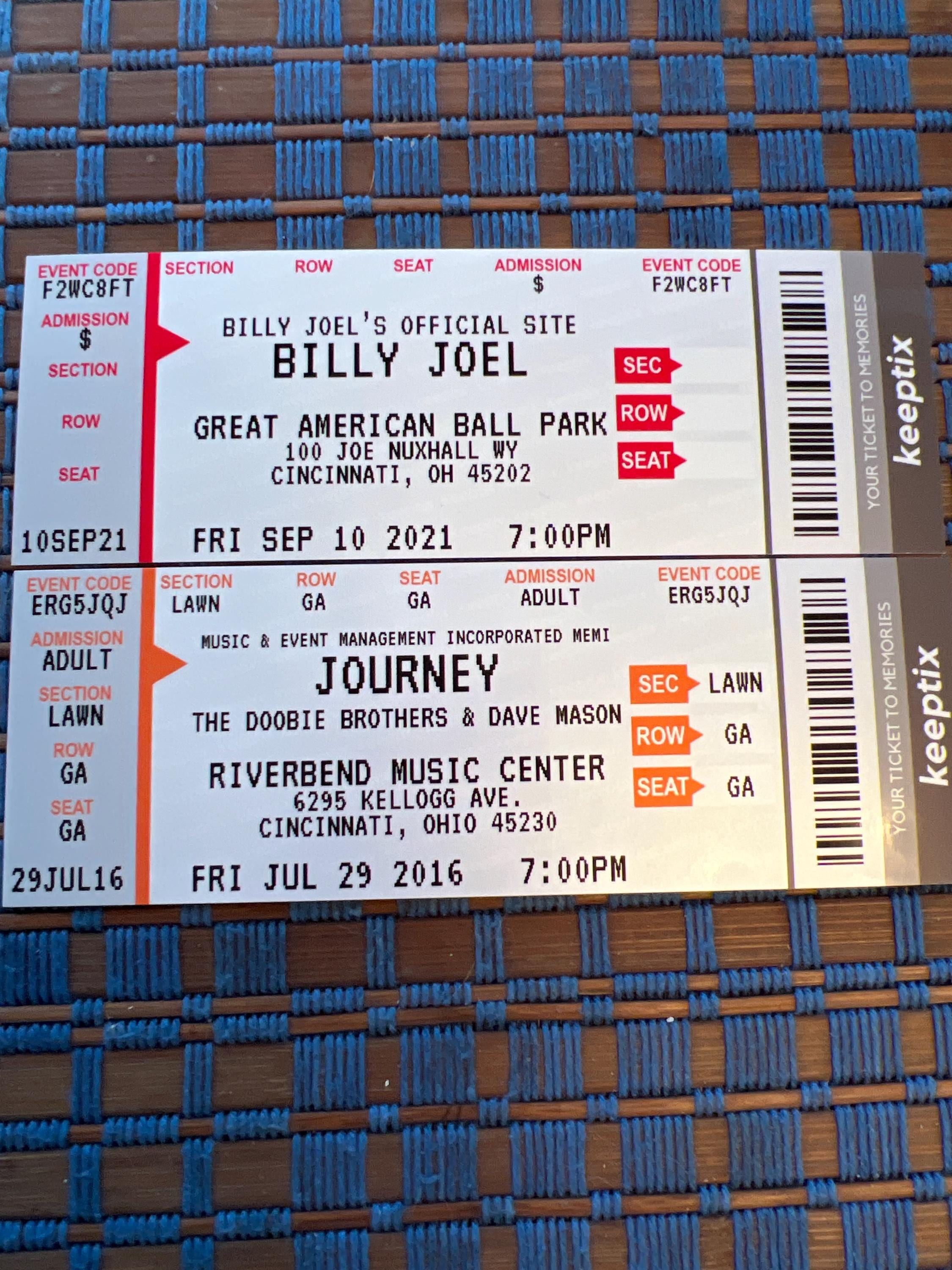 Two custom KeepTix souvenir tickets on a woven surface